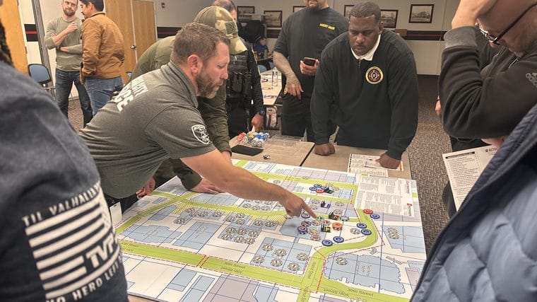 Responders gathered around a Counterstrike map, placing resource chips as they work a scenario together