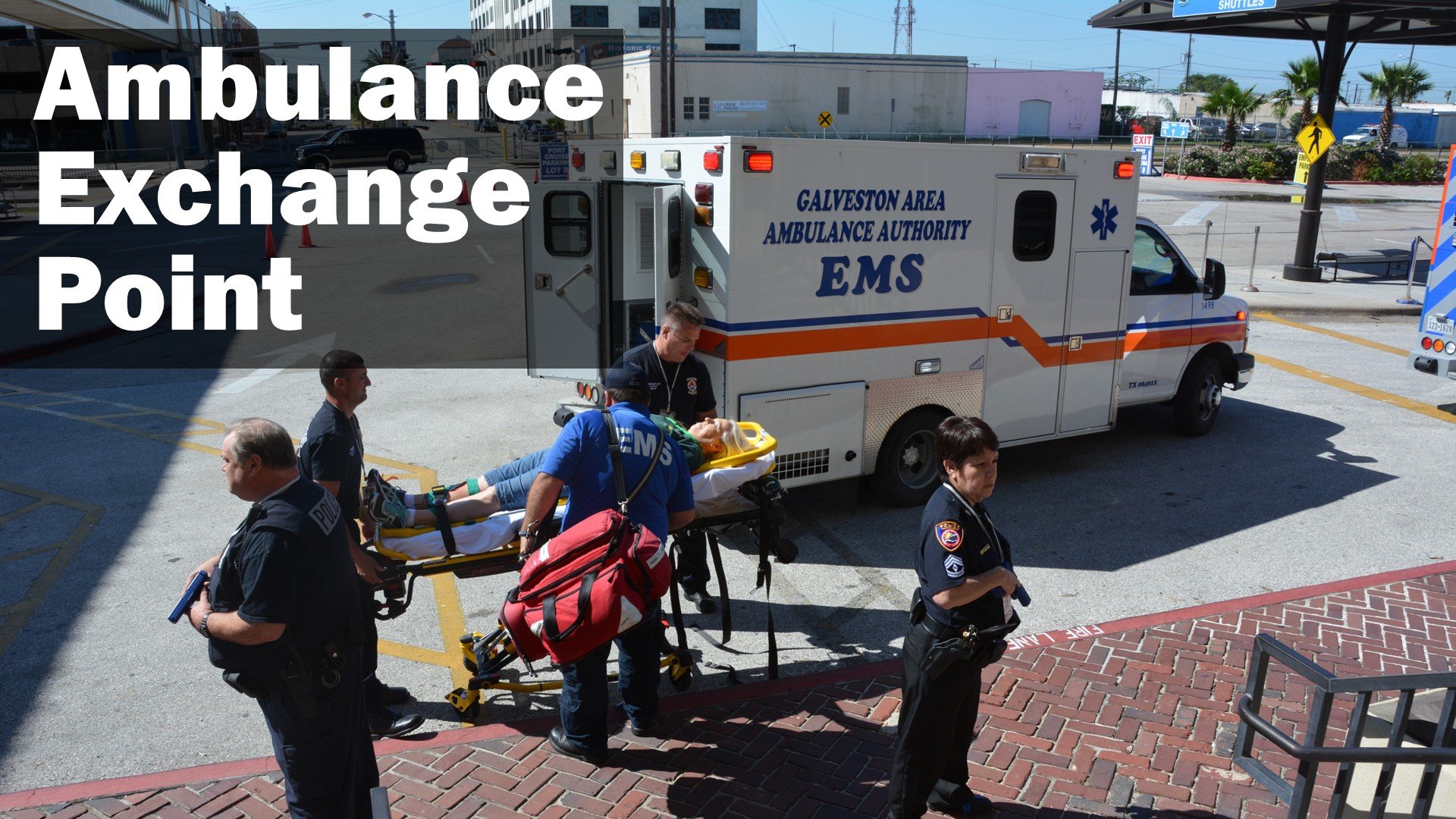 Ambulance Exchange Point training exercise: EMS crews load a patient on a stretcher into an ambulance while police officers provide security